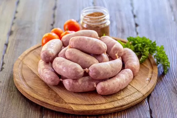 Raw sausage with spice and tomatoes on wooden background