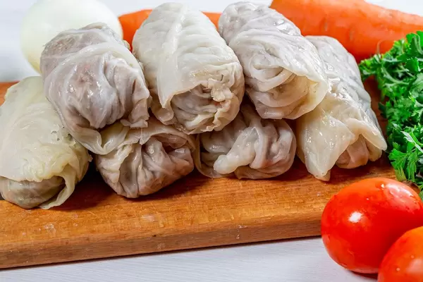 Raw stuffed cabbage on the kitchen Board with fresh tomatoes and herbs (Flip 2019)