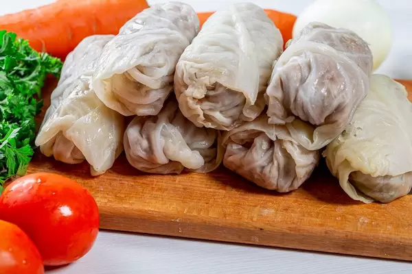 Raw stuffed cabbage on the kitchen Board with fresh tomatoes and herbs