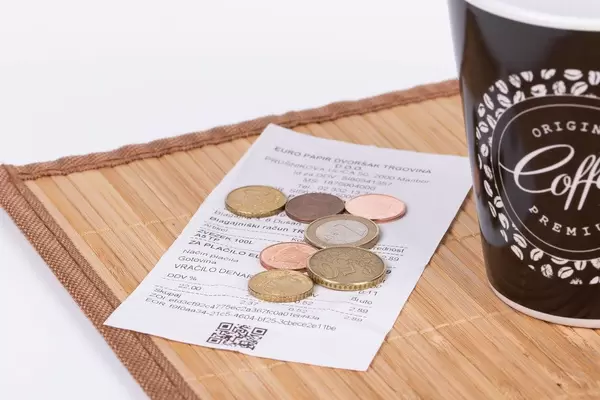 Receiept and coins on wooden plate