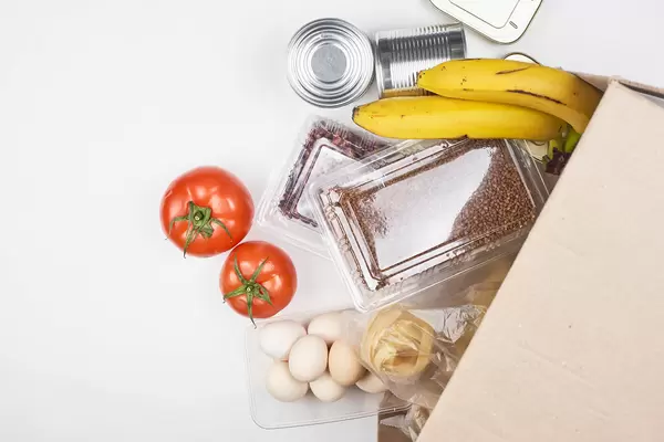 Receiving a donation from the food bank: eggs, tomatoes, nuts, fruit, tin cans with copy space