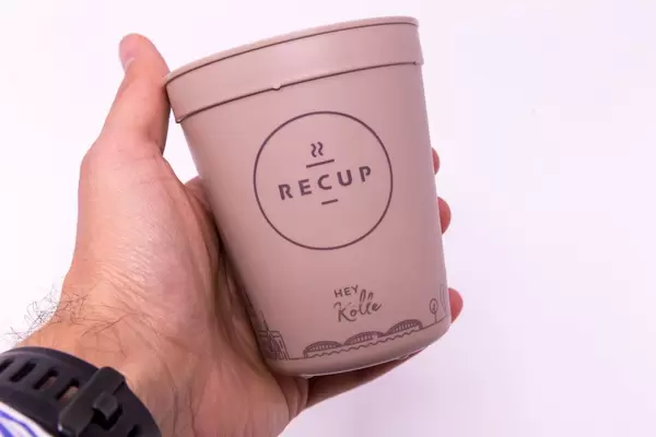 RECUP Kaffebecher - Hey Kölle in einer Hand gehalten