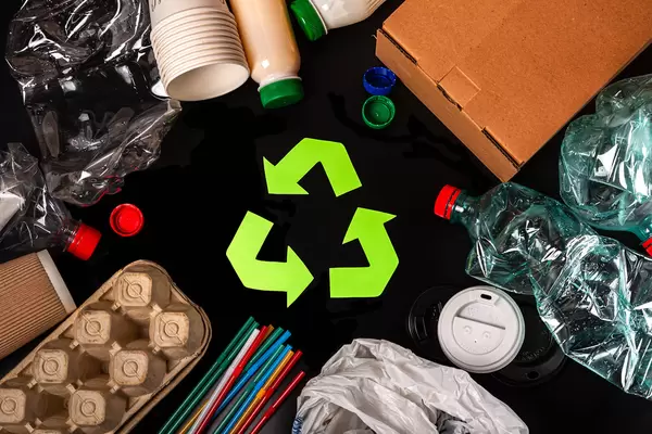 Recycled arrows sign near materials for recycle and reuse on black background, top view