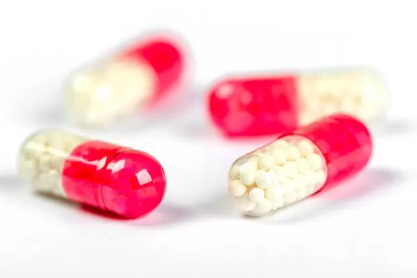 Red and white capsules with round medicine balls inside, close-up