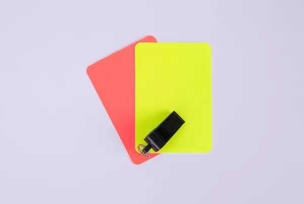 Red and yellow referee cards and a whistle for the referee