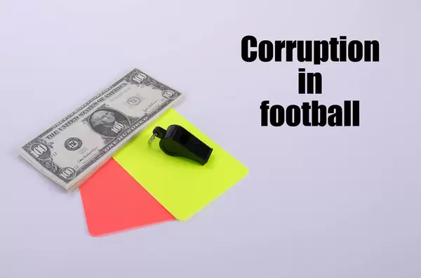 Red and yellow referee cards and a whistle with dollar banknotes and Corruption in football text