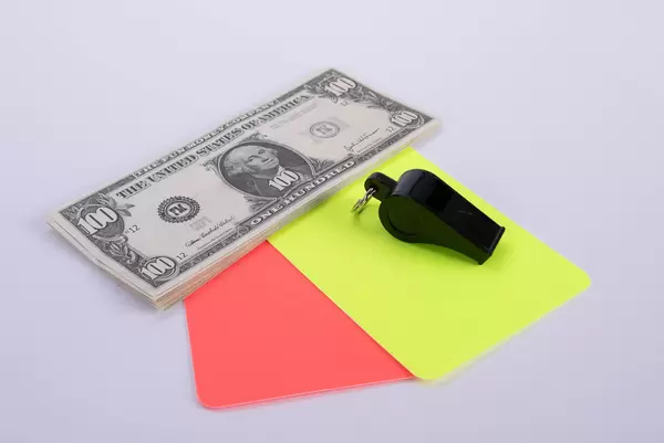 Red and yellow referee cards and a whistle with dollar banknotes