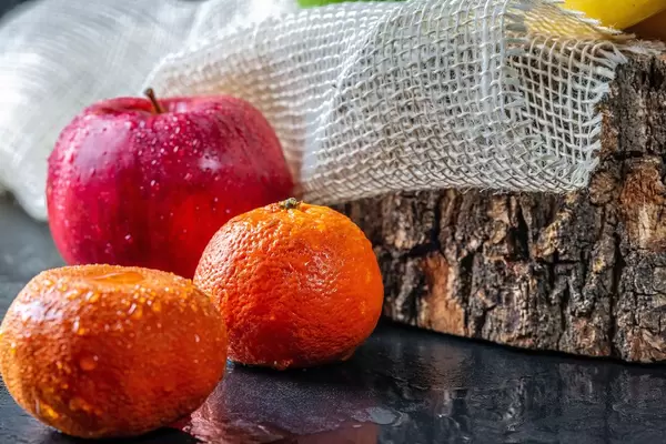 Red apple and tangerines with water drops on dark background