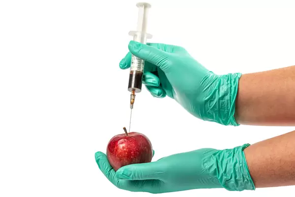 Red apple,injection needle or syringe and chemical in hand on white background.Concept pesticide residues in apple,fruits and vegetables