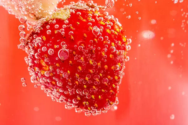 Red background with fresh strawberries and bubbles