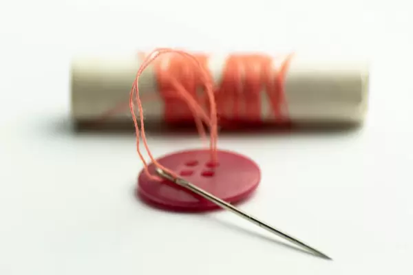Red button with orange thread on a spool