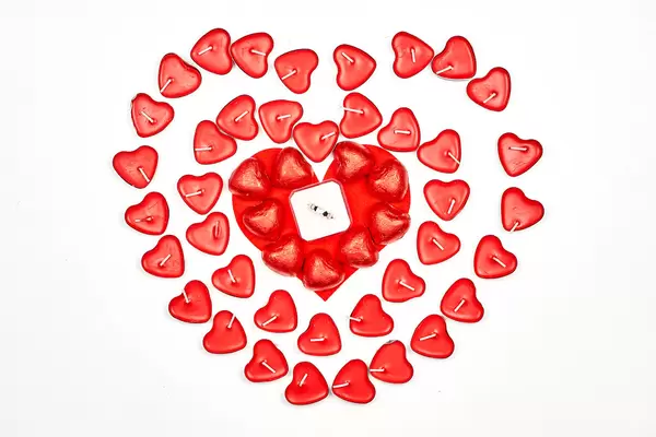 Red candles in heart form and wedding ring in the box