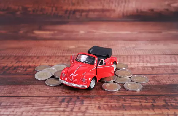 Red cars with coins on wooden table