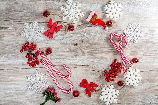 Red Christmas decor and white snowflakes on wooden background with free space