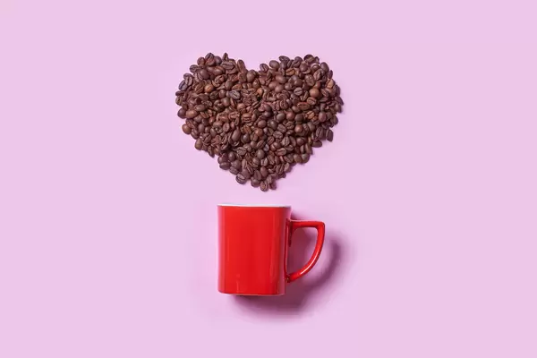 Red coffee cup and raw coffee beans in shape of heart