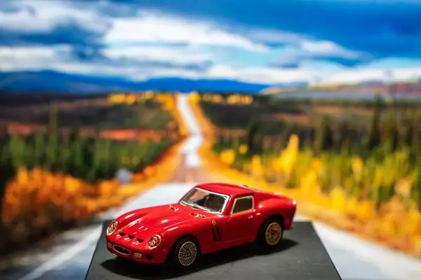 Red Ferrari toy car on platform with scenery background