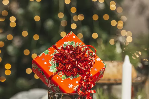 Red gift box with bow on golden bokeh background