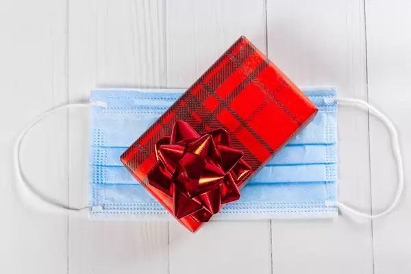 Red gift box with bow on medical mask, top view