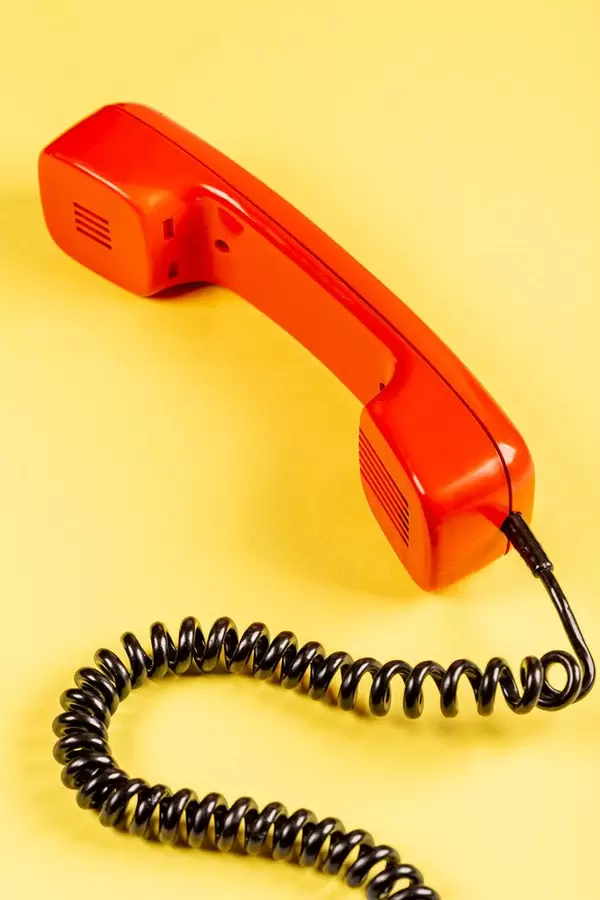 Red handset of phone old model on a yellow background