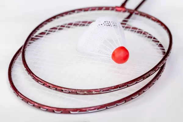 Red metal badminton rackets and a white shuttlecock