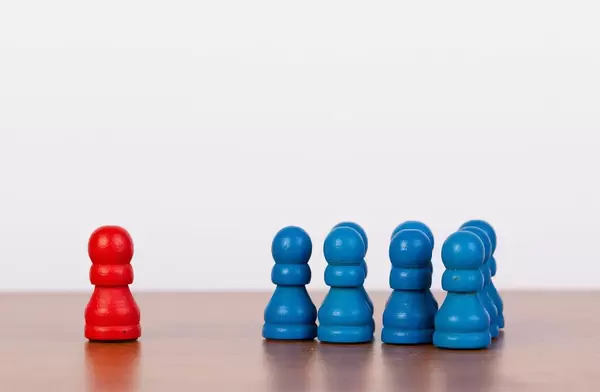 Red pawn figure against united blue figurines