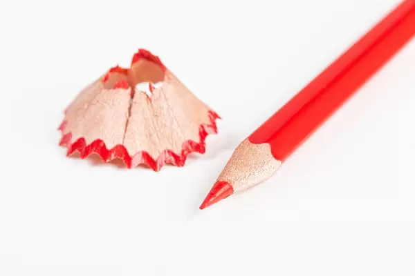 Red pencil and shavings on a white background