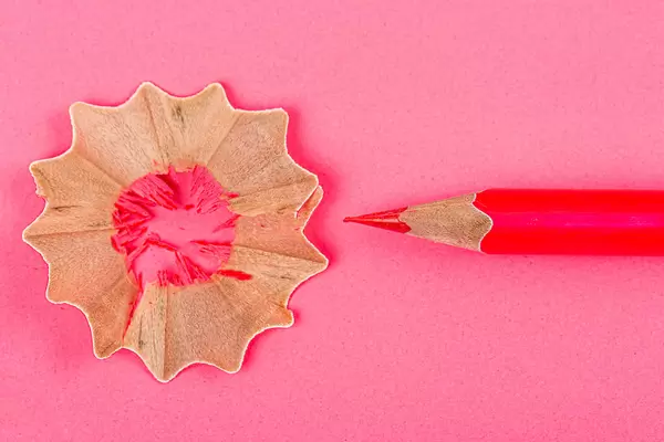 Red pencils with pencil shavings on red background