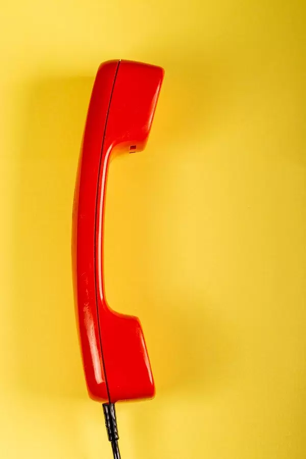 Red phone receiver on yellow background