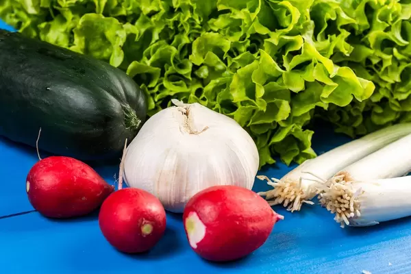 Red radishes Onion Garlic Cucumber and Lettuce on the wooden board