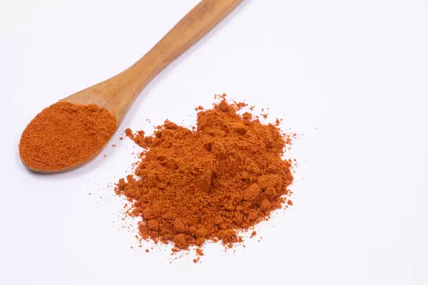 Red spicy Paprika powder with wooden spoon on the white background
