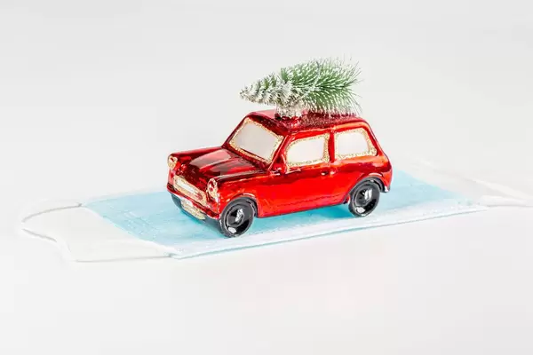 Red toy car with christmas tree and medical mask