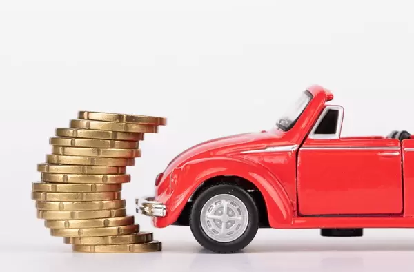 Red toy car with stack of coins on white background