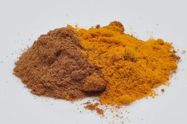Reddish spices on a white table: cinnamon and turmeric
