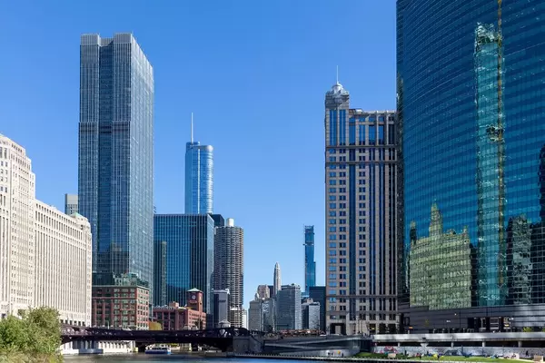Reflection of skyscrapers in the curved green glass facade of the Nuveen global headquarters building by the Chicago River
