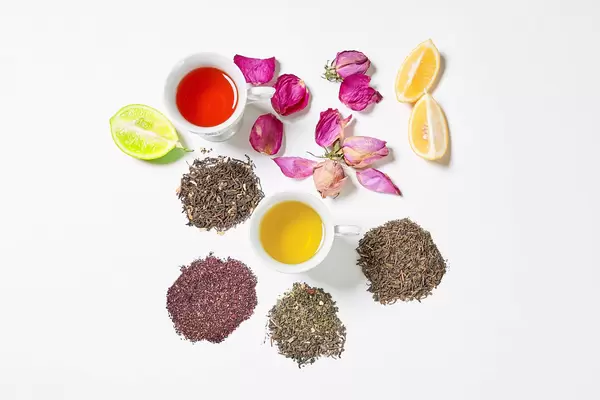 Refreshing tea cups on white with dry tea leafs and fruits