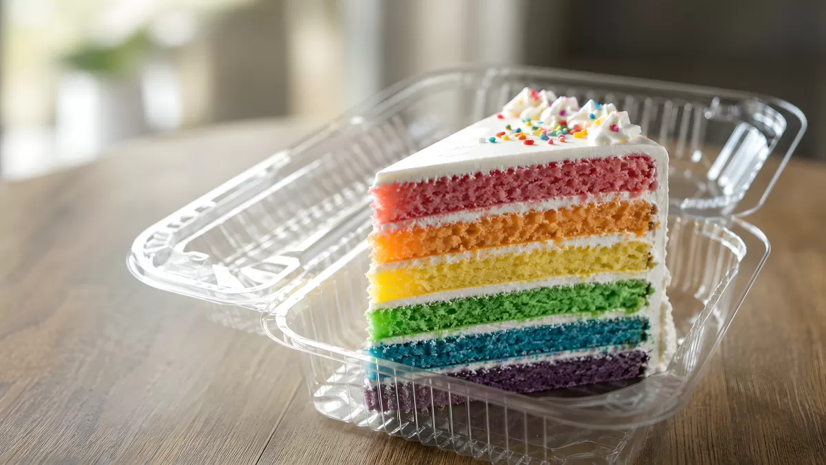 Regenbogentorte in Transportbox auf Holztisch
