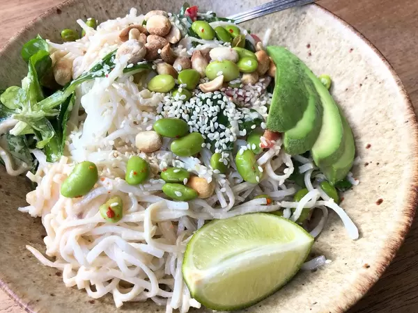 Reisnudeln mit Tamari-Ingwer-Dressing, Avocado, Edamame, Paprika, Sesam, Feldsalat, Erdnüssen, Minze und Limette (kalt serviert)