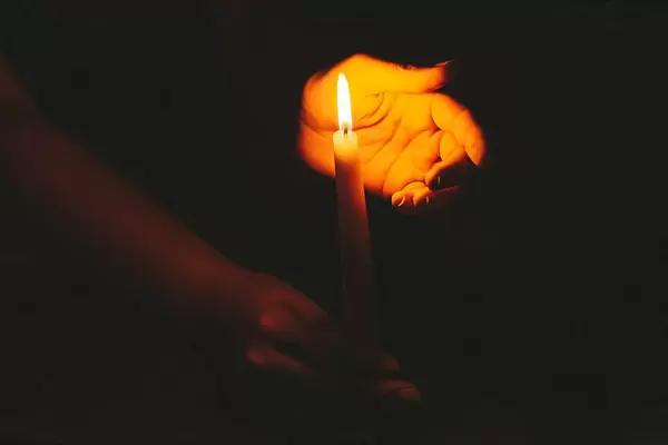 Religious concept, hands holding a burning candle on dark background