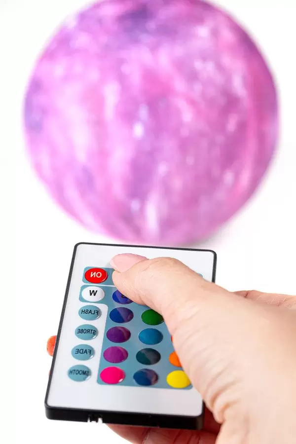 Remote control in a woman's hand, in the background nightlight-planet (Flip 2019)