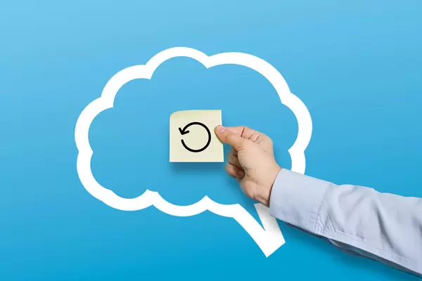 Restart your mind - hand holds a sticker with restart symbol over brain shape