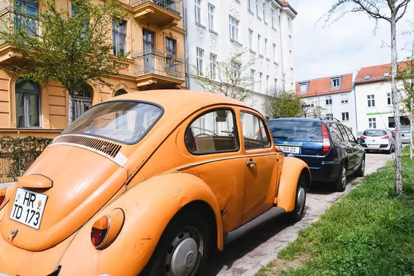 Retro-Auto und originaler, oranger VW Beetle in einer deutschen Stadt geparkt