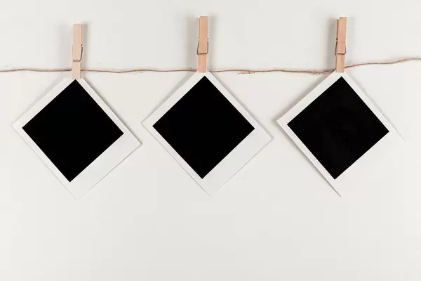 Retro photo frames hanging on rope on white background