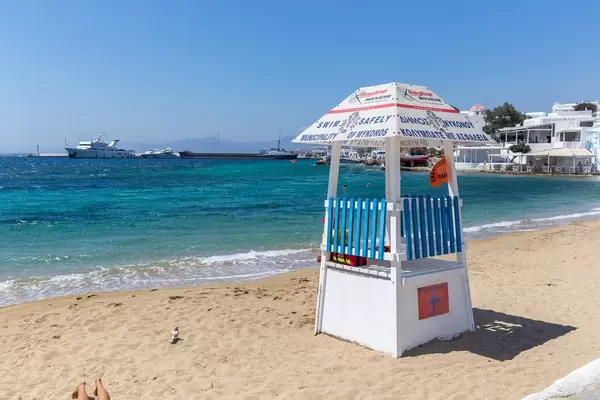 Rettungsschwimmer-Turm am Agia Anna Strand auf Mykonos (Griechenland) mit Fähre im Hintergrund