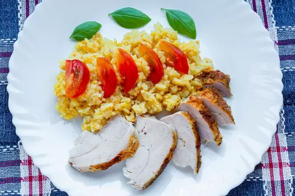 Rice with chicken fillet, tomato slices and fresh Basil leaves