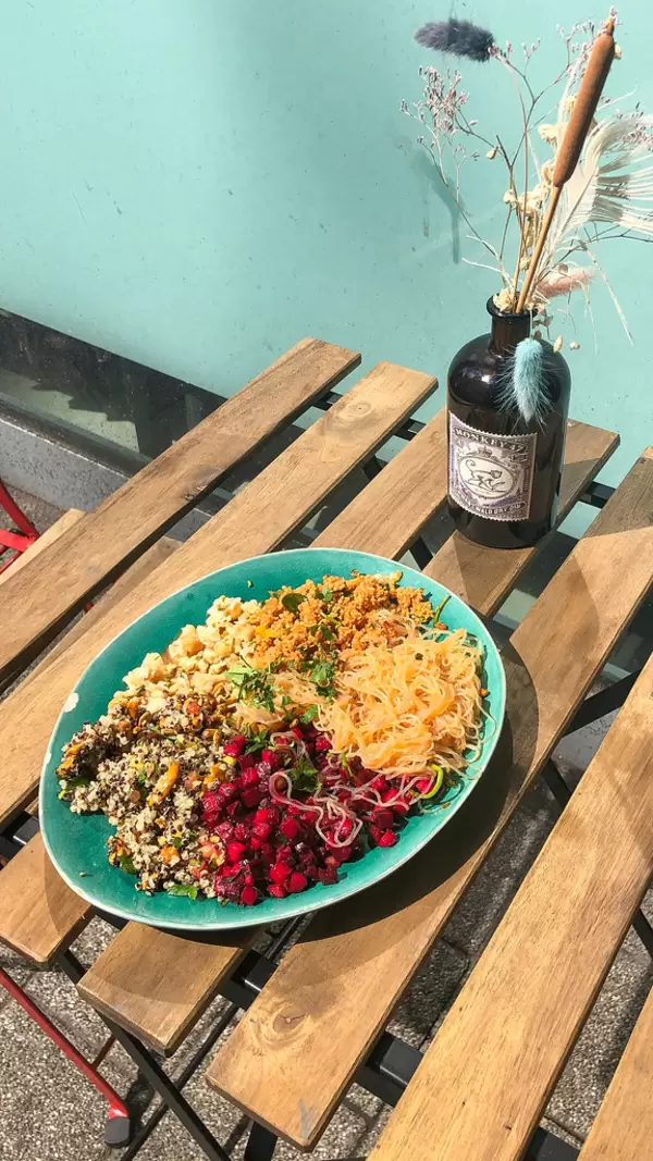 Rich vegan bowl with couscous, cauliflower salad, beetroot, pasta and quinoa served on blue plate