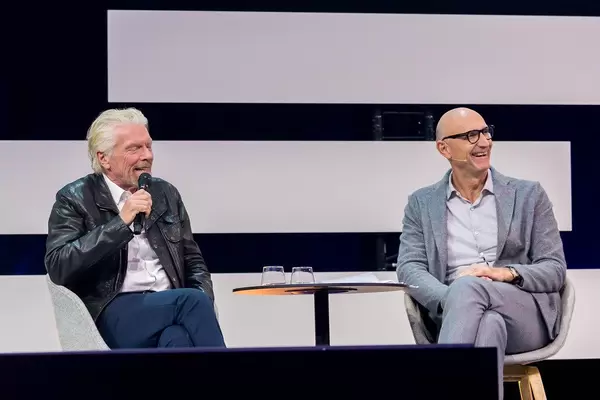 Richard Branson and Tim Höttges look at the stage and smile