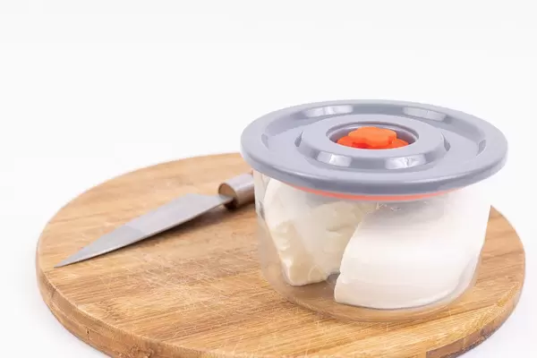 Ricota Cheese in the vacuum bowl on the wooden board