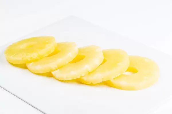 Rings of sweet canned pineapple on a white kitchen board