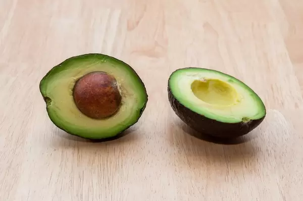 Ripe Avocado cut in half on a wooden background