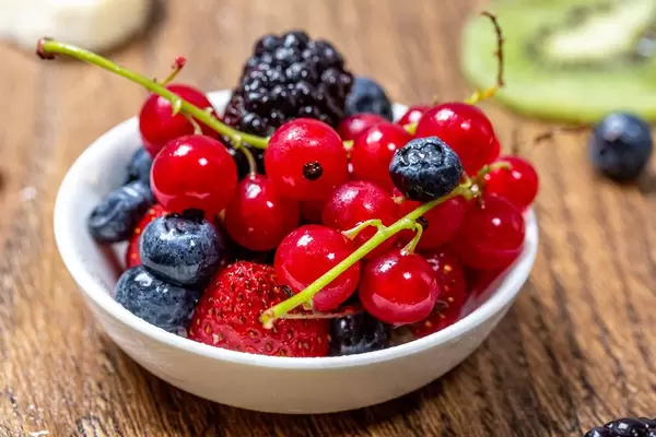 Ripe berries in a bowl on a wooden table